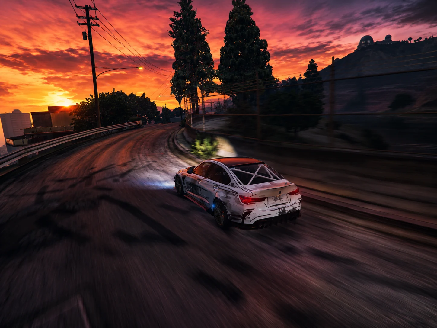 A race car takes a corner in the Los Santos hills at sunset.